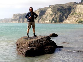 Thomas stands on a rock in the sea